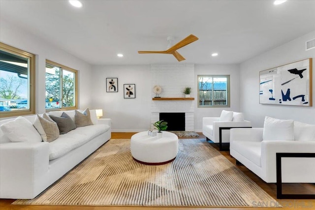 living room with a fireplace, ceiling fan, and hardwood / wood-style floors