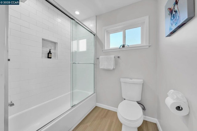 bathroom featuring bath / shower combo with glass door, hardwood / wood-style floors, and toilet