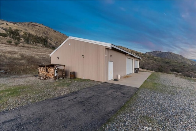 property exterior at dusk featuring a garage, a mountain view, and an outdoor structure