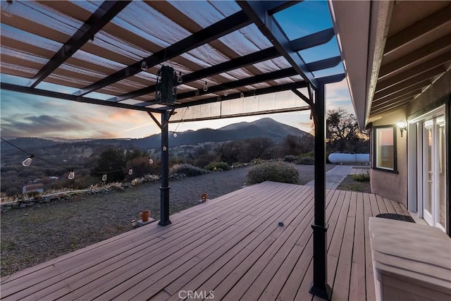 deck at dusk with a mountain view and a pergola