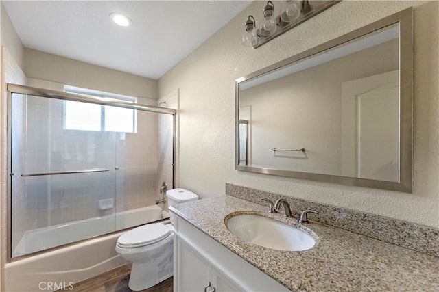 full bathroom featuring wood-type flooring, shower / bath combination with glass door, vanity, and toilet