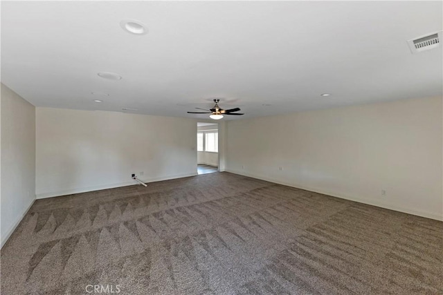 empty room with ceiling fan and dark colored carpet