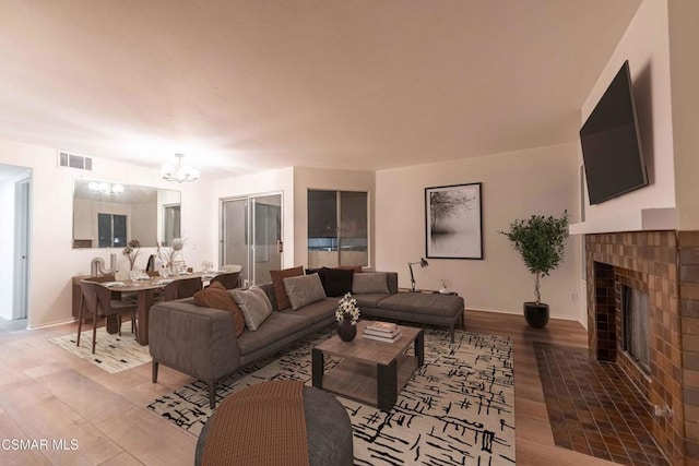 living room featuring an inviting chandelier, a fireplace, and wood-type flooring