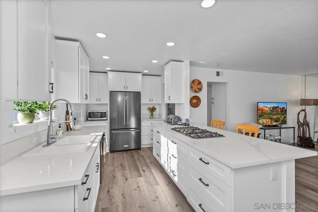 kitchen with sink, white cabinets, a center island, and appliances with stainless steel finishes