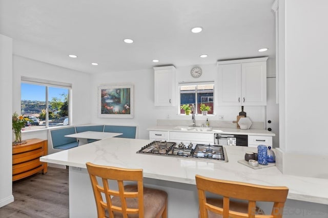 kitchen featuring sink, white cabinetry, a kitchen bar, and stainless steel gas cooktop