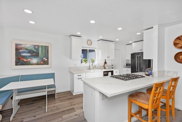 kitchen with stainless steel appliances, sink, white cabinets, a kitchen breakfast bar, and kitchen peninsula