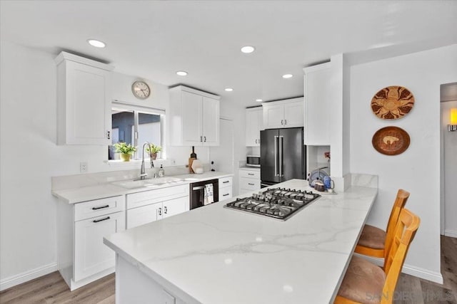 kitchen with white cabinets, a breakfast bar area, stainless steel appliances, kitchen peninsula, and sink