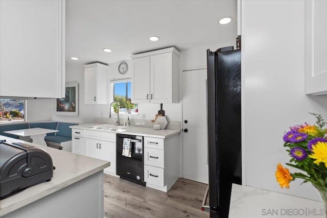 kitchen with white cabinets, light wood-type flooring, black appliances, and sink