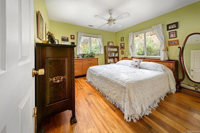 bedroom with ceiling fan, multiple windows, and wood-type flooring