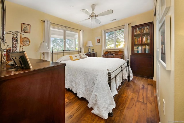 bedroom with dark hardwood / wood-style flooring, ceiling fan, and multiple windows