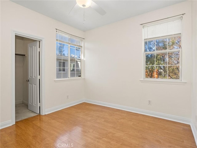 unfurnished bedroom featuring light wood-type flooring, ceiling fan, a spacious closet, and a closet