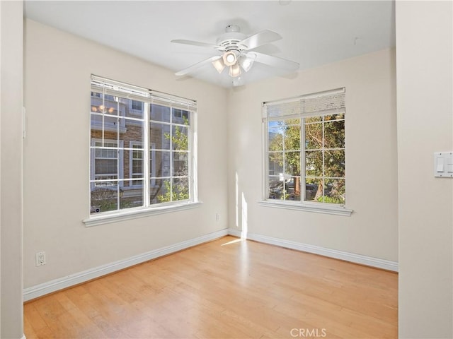 spare room with ceiling fan, light wood-type flooring, and a wealth of natural light