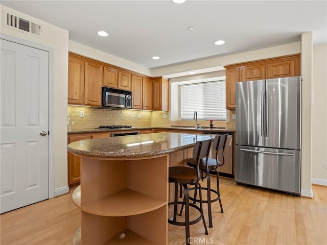 kitchen with sink, stainless steel appliances, light hardwood / wood-style flooring, and a center island