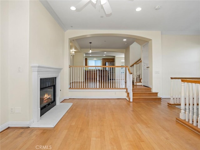 unfurnished living room with light hardwood / wood-style floors, ceiling fan, and crown molding