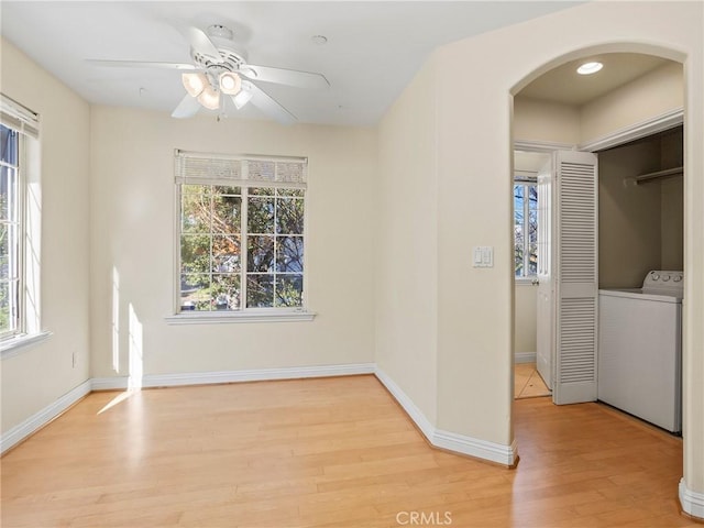 unfurnished room with washer / dryer, ceiling fan, light hardwood / wood-style flooring, and a wealth of natural light