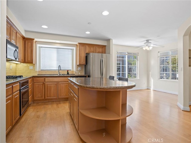 kitchen with sink, a center island, light hardwood / wood-style flooring, decorative backsplash, and appliances with stainless steel finishes