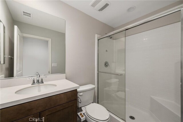 bathroom with vanity, a shower with door, and toilet