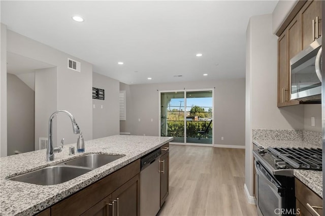 kitchen featuring light hardwood / wood-style floors, light stone countertops, stainless steel appliances, and sink