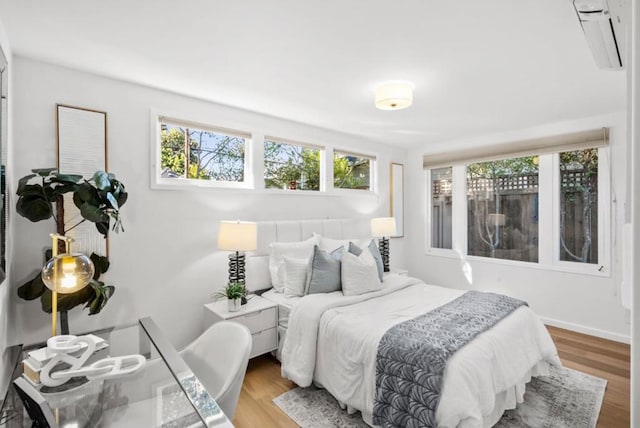 bedroom with hardwood / wood-style flooring and a wall mounted air conditioner