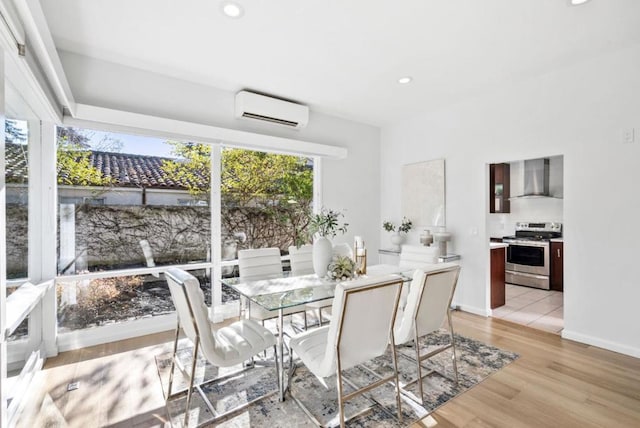 dining area with light hardwood / wood-style floors and a wall mounted air conditioner