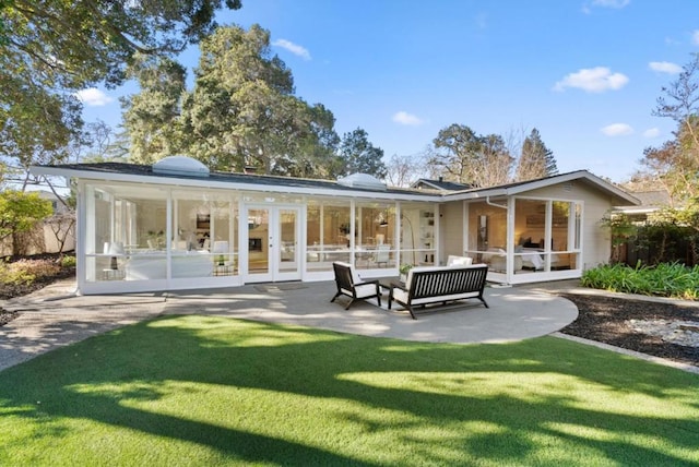 back of property featuring french doors, a sunroom, a lawn, a patio, and an outdoor hangout area