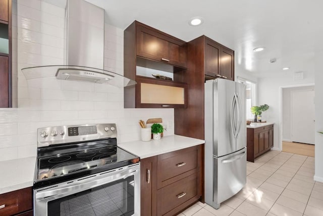 kitchen with stainless steel appliances, light tile patterned floors, wall chimney exhaust hood, and decorative backsplash