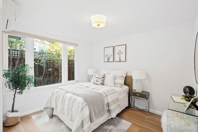 bedroom featuring hardwood / wood-style flooring and a wall mounted air conditioner