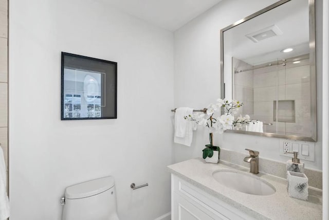 bathroom with a shower with door, toilet, and vanity