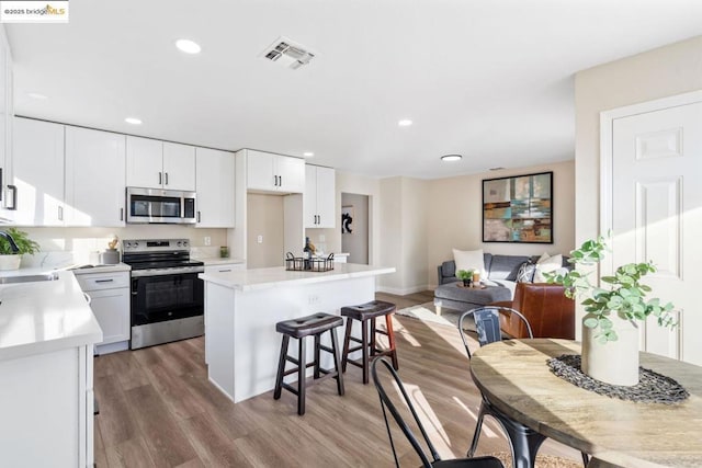 kitchen featuring stainless steel appliances, sink, white cabinetry, a center island, and light hardwood / wood-style flooring