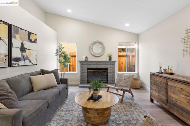 living room featuring a wealth of natural light, hardwood / wood-style floors, lofted ceiling, and a fireplace