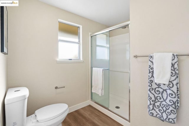 bathroom with toilet, hardwood / wood-style floors, and a shower with shower door