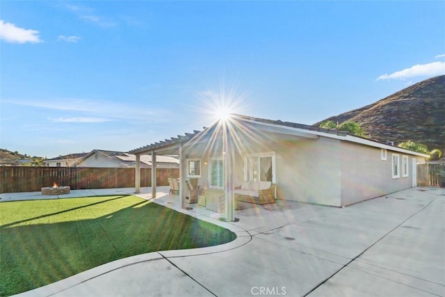 rear view of house with a lawn, a patio area, a pergola, and a fire pit