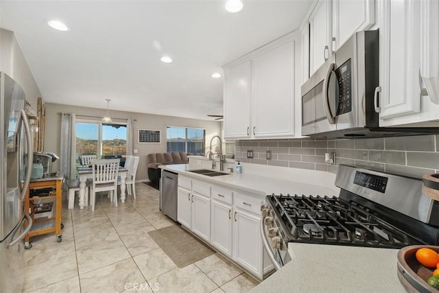 kitchen with stainless steel appliances, white cabinetry, sink, and pendant lighting