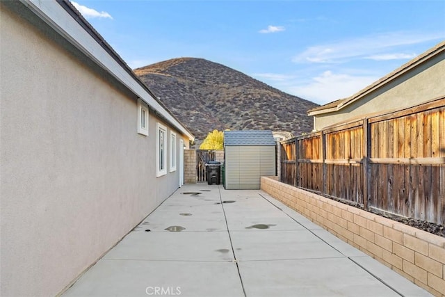 view of patio with a mountain view and a shed