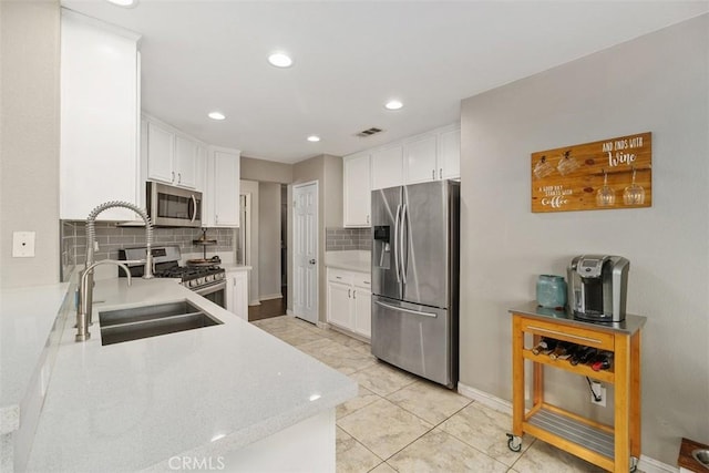 kitchen featuring appliances with stainless steel finishes, white cabinets, sink, and tasteful backsplash