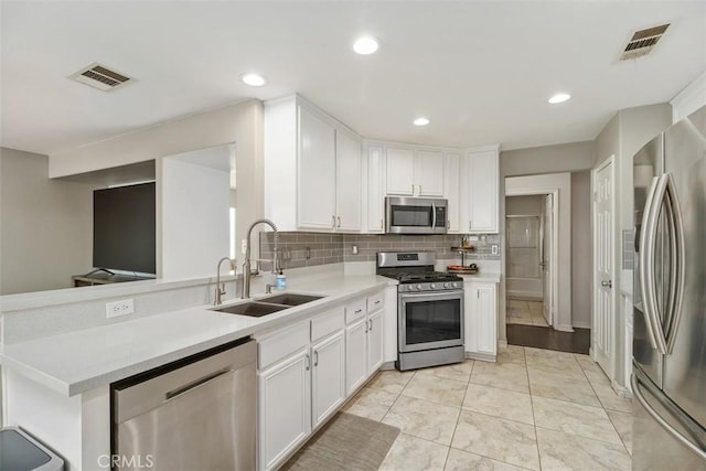 kitchen with stainless steel appliances, white cabinetry, sink, and tasteful backsplash