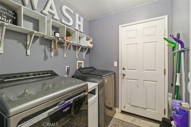 washroom with washing machine and dryer and light tile patterned floors