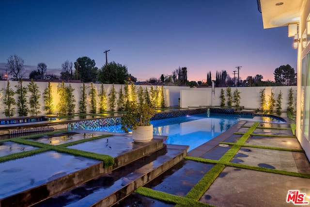 pool at dusk featuring a patio area