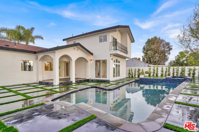 rear view of property featuring a patio area, a balcony, and a swimming pool with hot tub