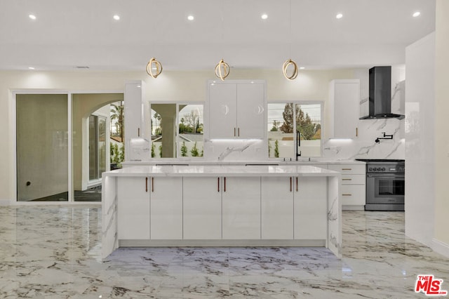 kitchen with high end range, white cabinets, tasteful backsplash, wall chimney range hood, and pendant lighting