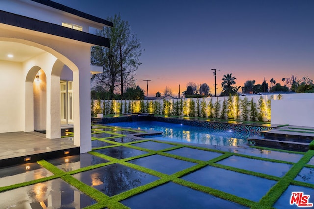 pool at dusk with a patio area