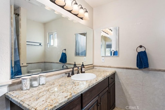 bathroom with tile walls, vanity, and toilet