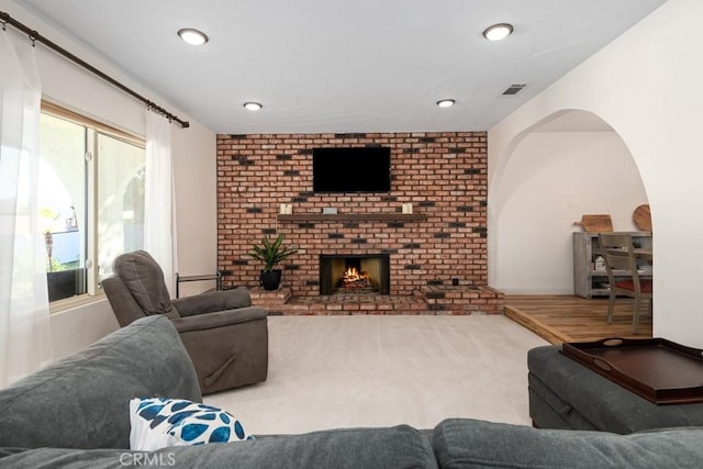 living room featuring a brick fireplace, a wealth of natural light, and hardwood / wood-style floors