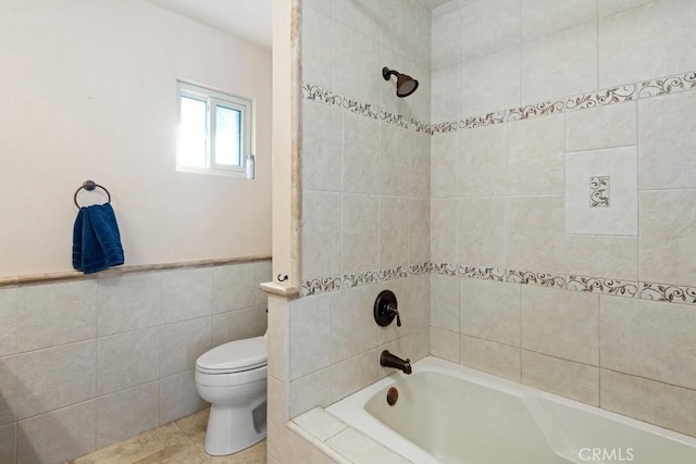 bathroom featuring toilet, tile patterned flooring, tile walls, and tiled shower / bath combo