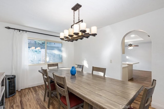 dining space featuring ceiling fan with notable chandelier and hardwood / wood-style flooring