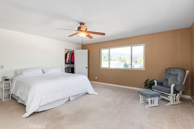 carpeted bedroom with a walk in closet, a closet, and ceiling fan