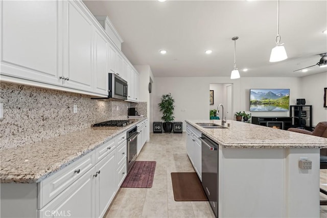 kitchen featuring a center island with sink, backsplash, pendant lighting, white cabinets, and sink