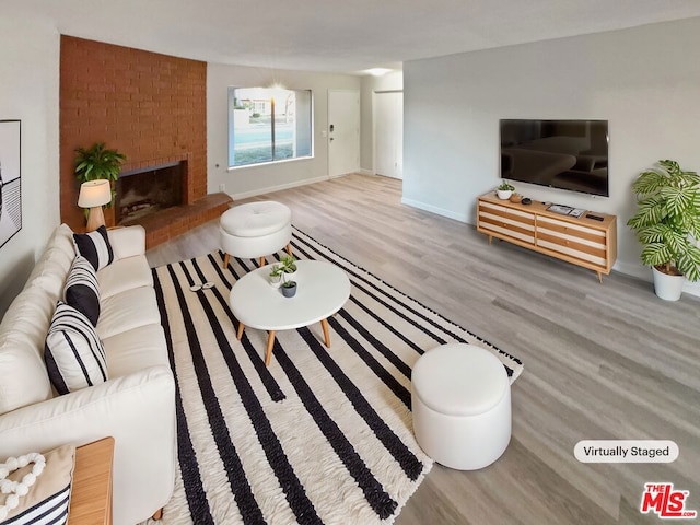 living room featuring a brick fireplace and wood-type flooring