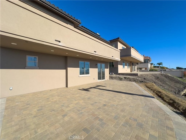 rear view of house featuring a patio and stucco siding