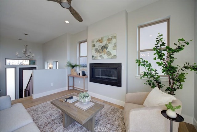 living room with a healthy amount of sunlight, baseboards, wood finished floors, and a glass covered fireplace